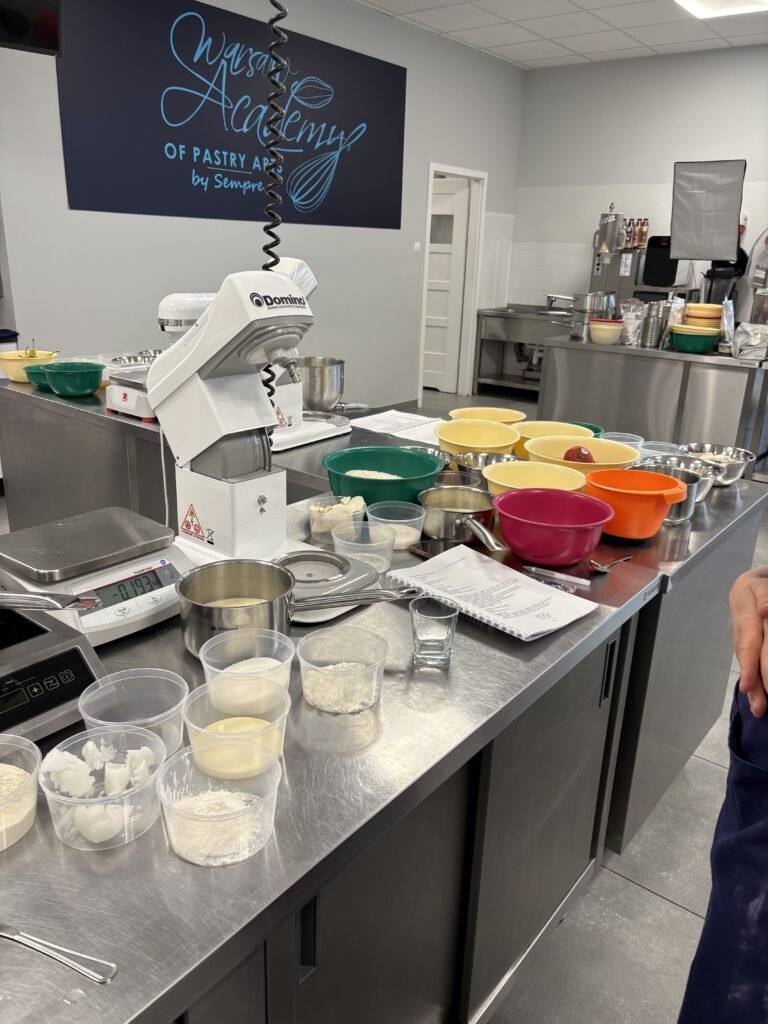 Stanowisko cukiernicze z miskami, wagą i składnikami przygotowanymi do wypieków w profesjonalnej kuchni.