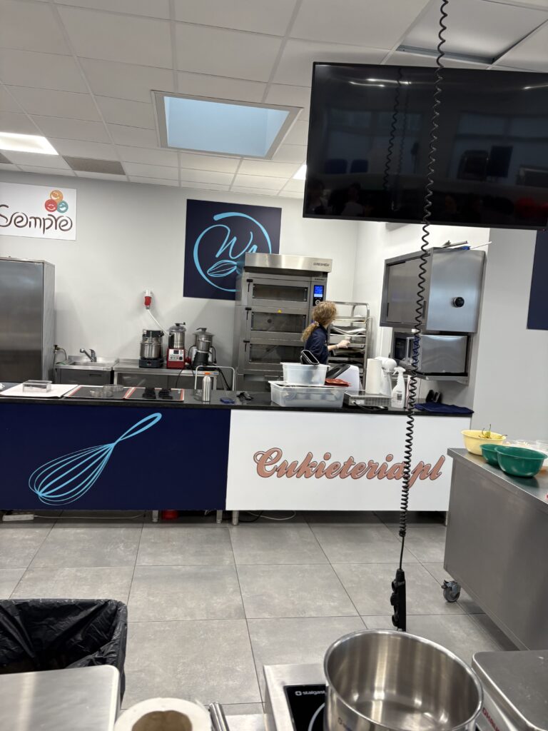 Sala szkoleniowa z profesjonalnym stanowiskiem cukierniczym i sprzętem gastronomicznym.