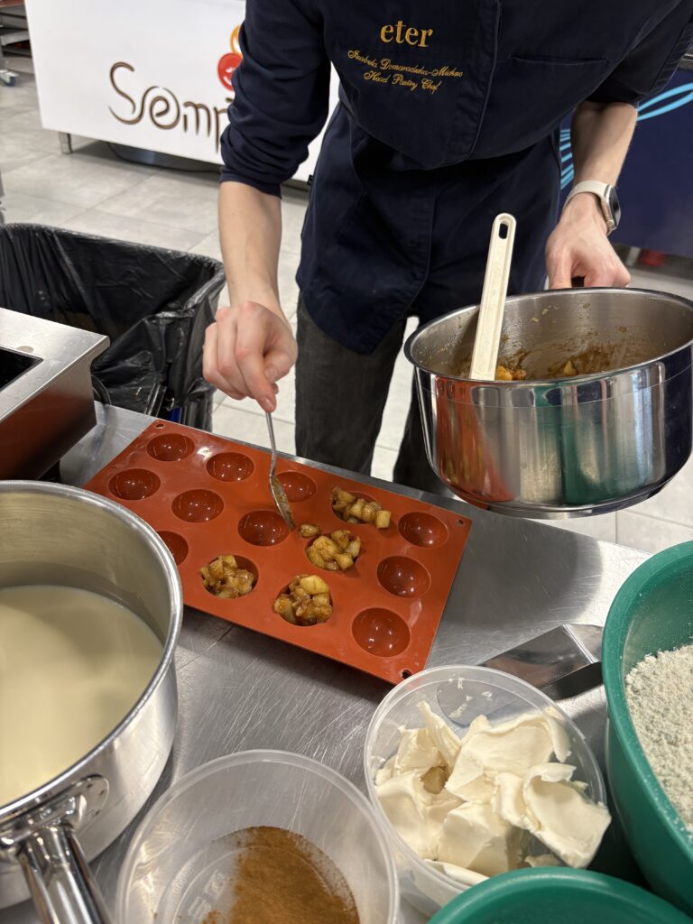 Nakładanie masy do silikonowej formy na muffiny w trakcie przygotowywania deseru.