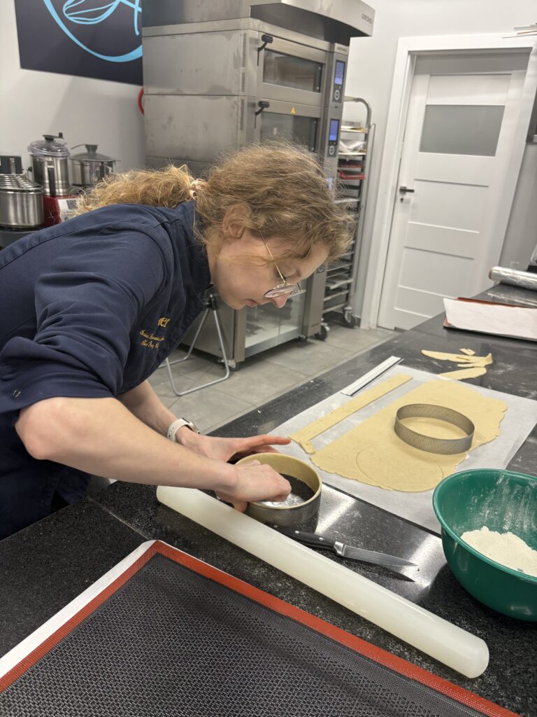 Wycinanie okręgu z rozwałkowanego ciasta przy użyciu metalowej obręczy cukierniczej.